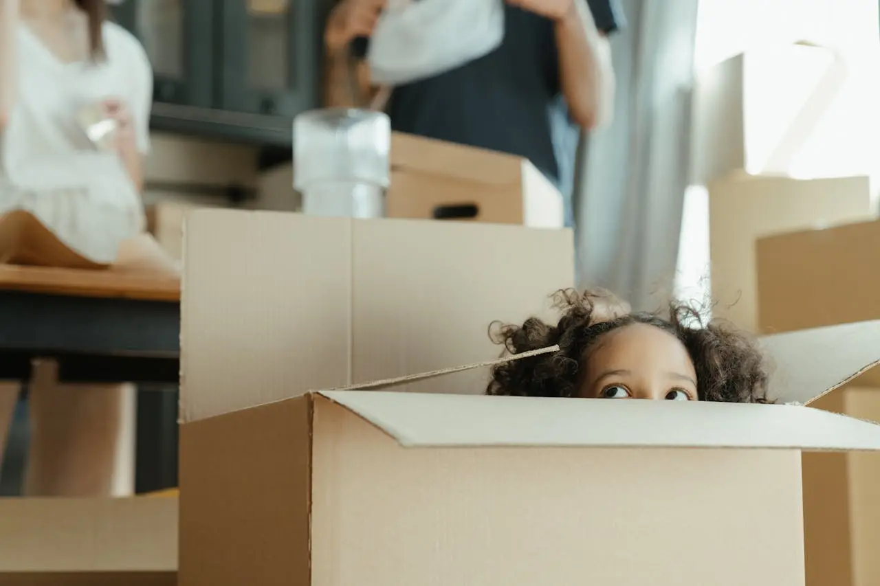 A child peeking from behind a cardboard box during household packing