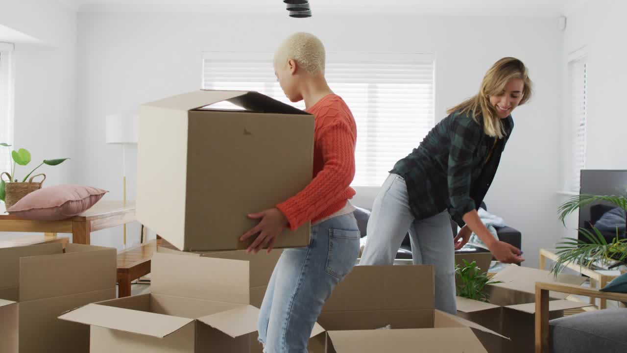 Two people packing cardboard boxes in a living room